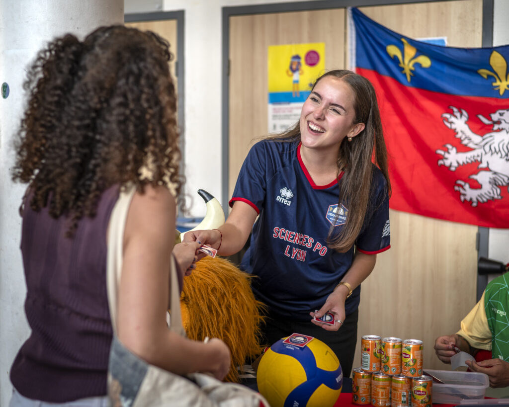 Elève qui sourit et qui donne un papier à une autre femme de dos