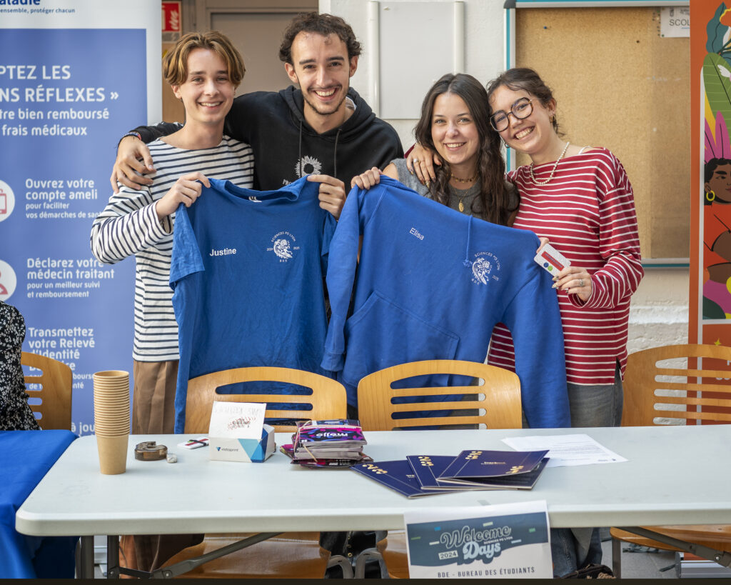 4 personnes debout qui tient un t-shirt et un pull du BDE de l'école